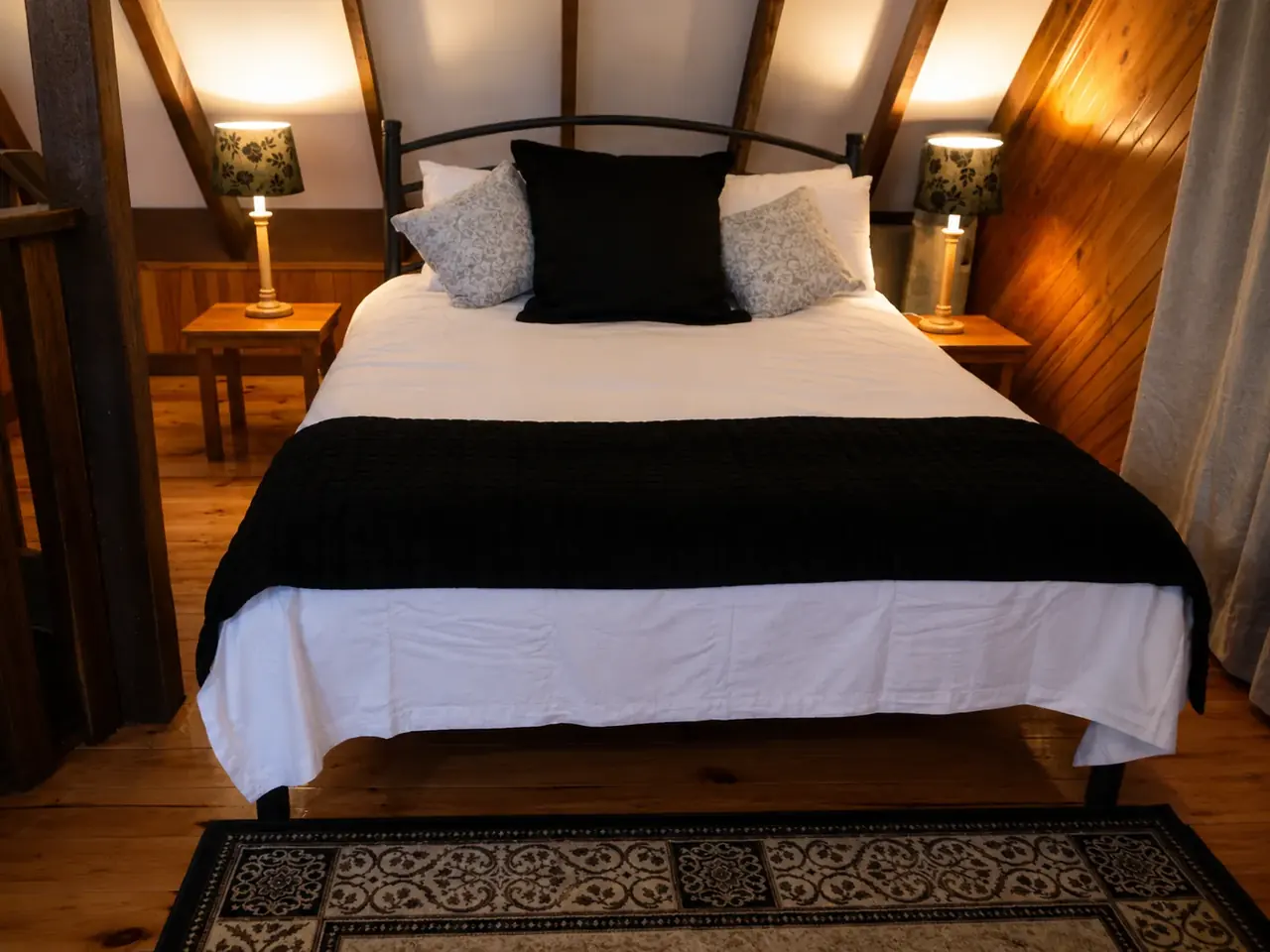 The queen bed and bedside lamps in a chalet at Beyonderup Falls
