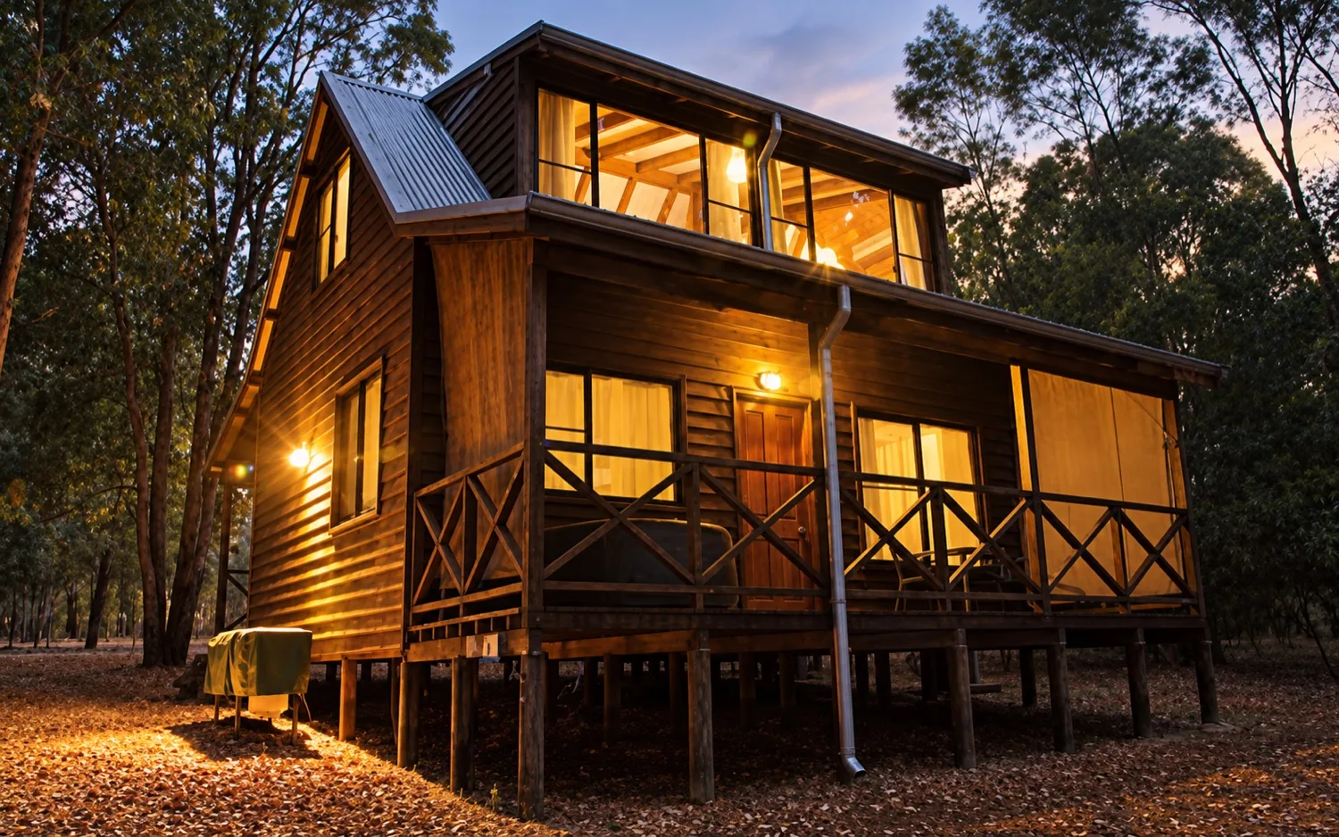 A timber chalet glowing at dusk, warm light in the windows among the trees