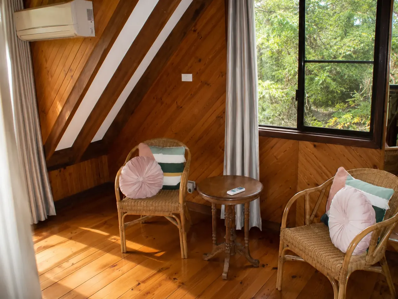 The loft sitting area, cane chairs beside the window onto the bush