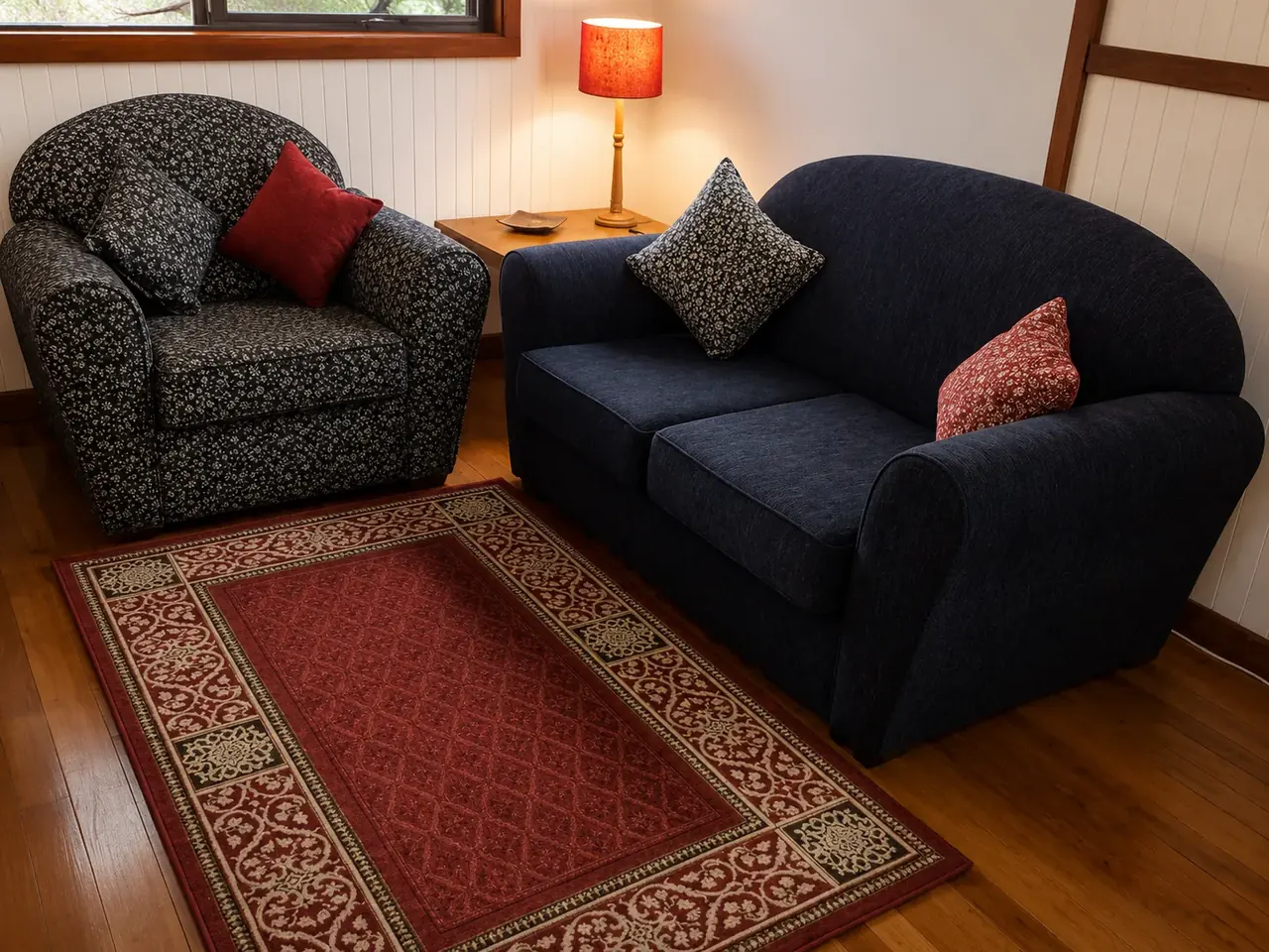 The lounge area inside a chalet, with sofa and armchairs on polished floorboards