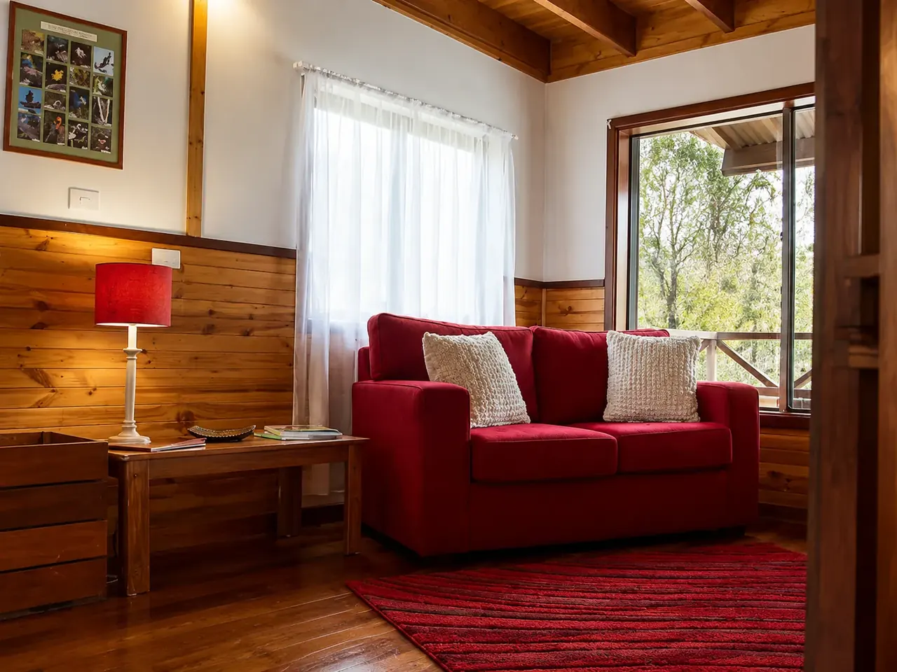 The lounge inside a chalet at Beyonderup Falls, with lamplight and a window onto the bush