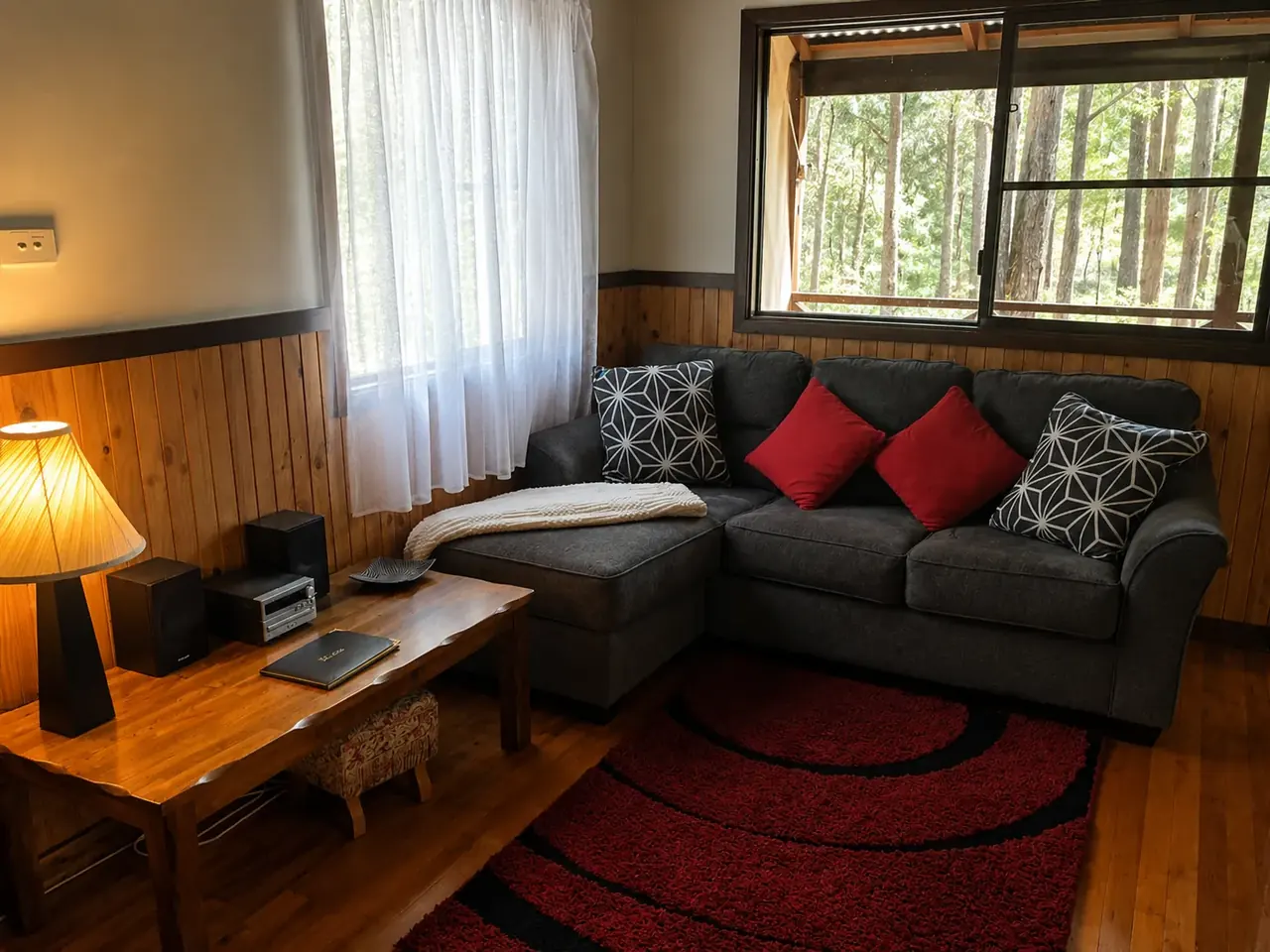 The lounge area inside a chalet, with sofa and rug on polished floorboards