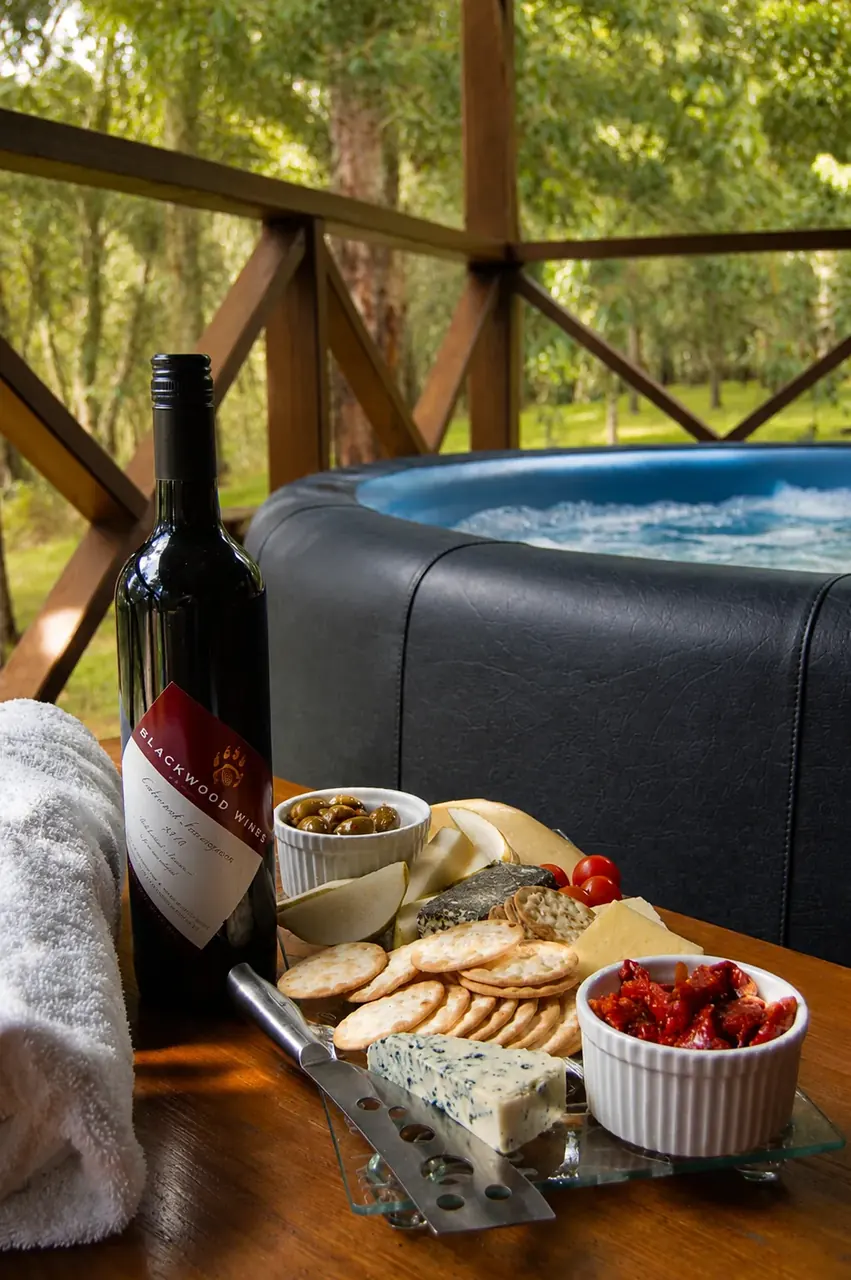 A bottle of wine and a cheese platter set beside the private heated spa
