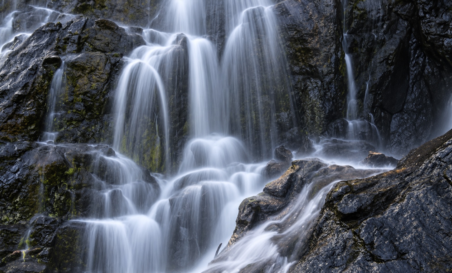 Beyonderup Falls in full winter flow, water streaming over dark mossy granite